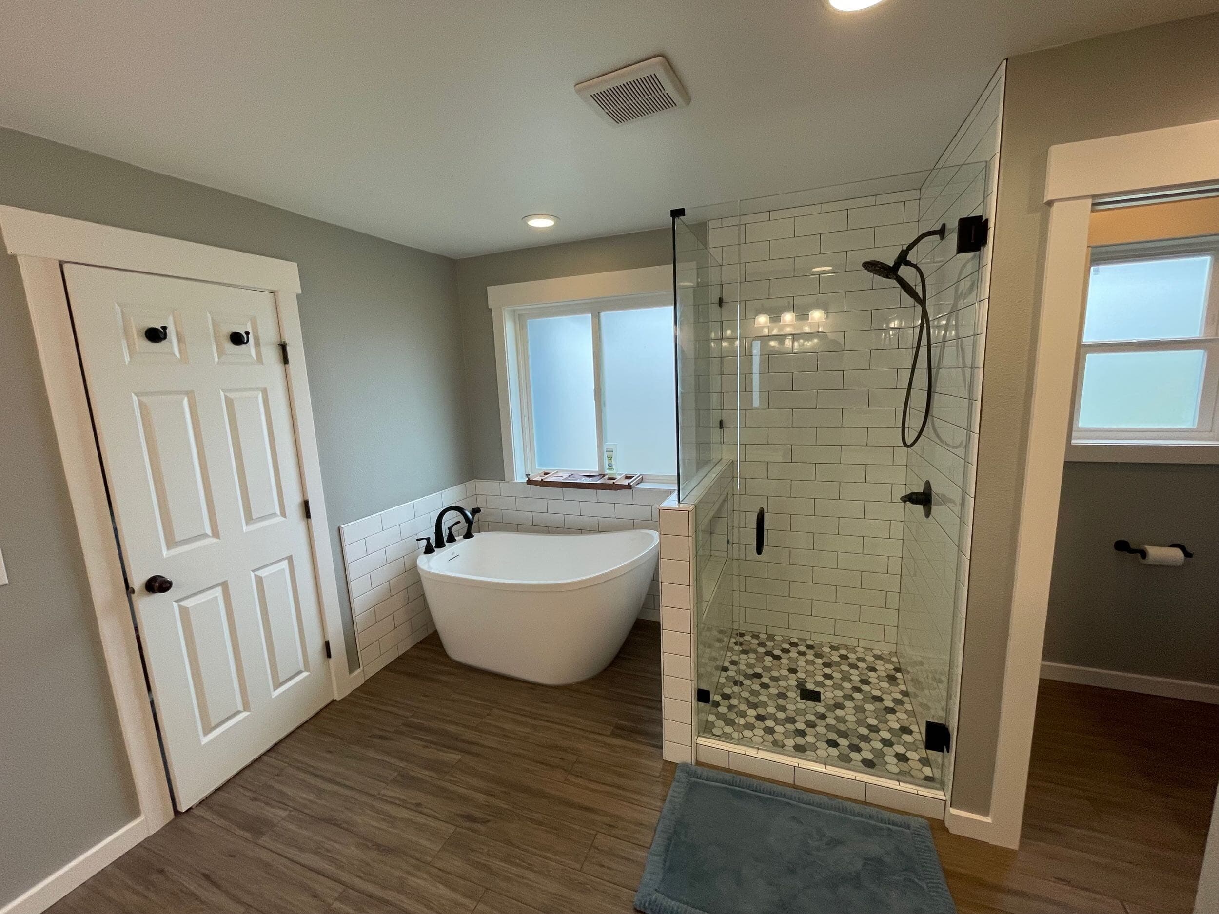 Bathroom remodel with freestanding tub, glass shower with mosaic tile pan, and subway-tile walls