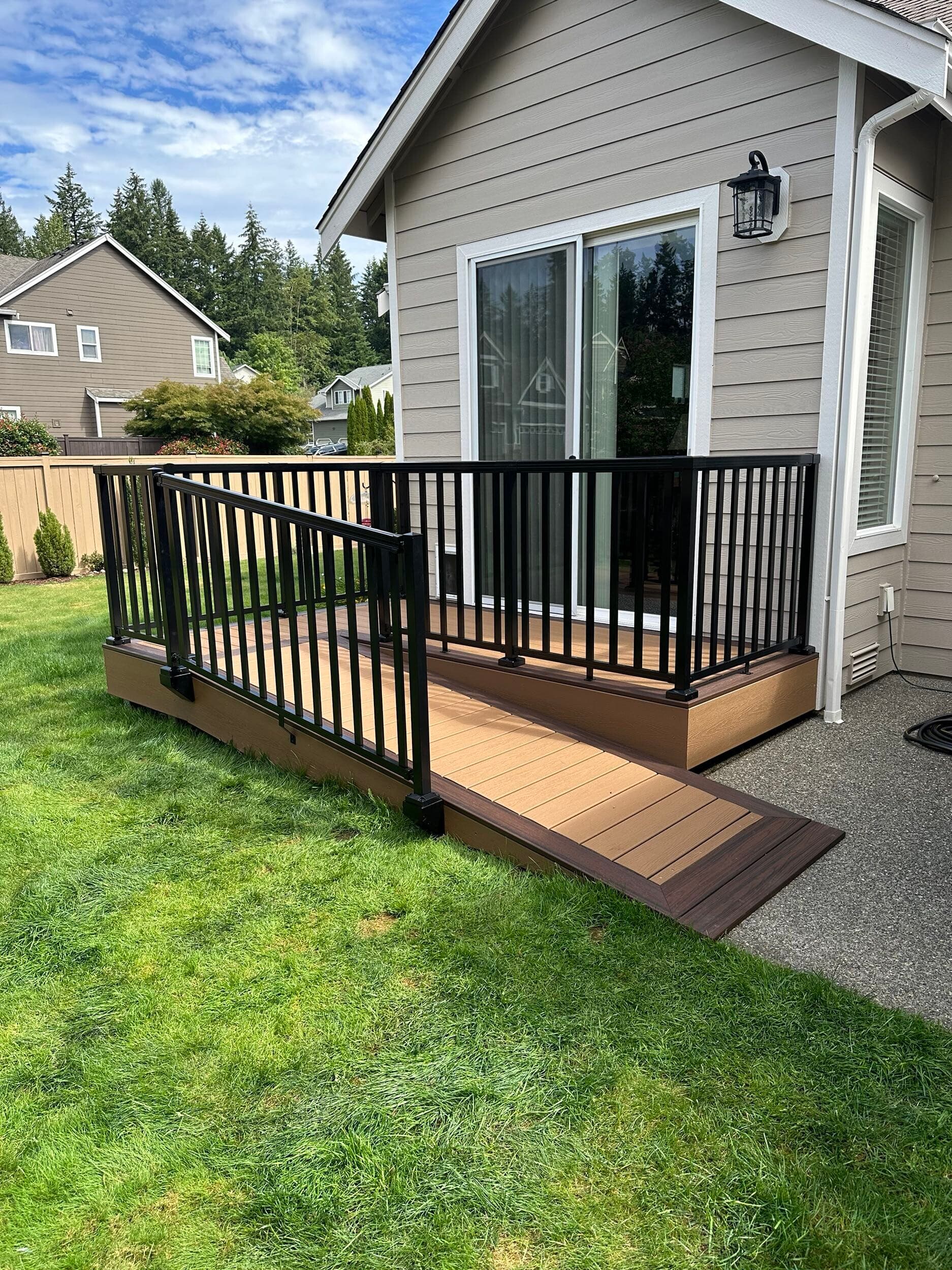 New backyard deck with black aluminum railing beside a gray house