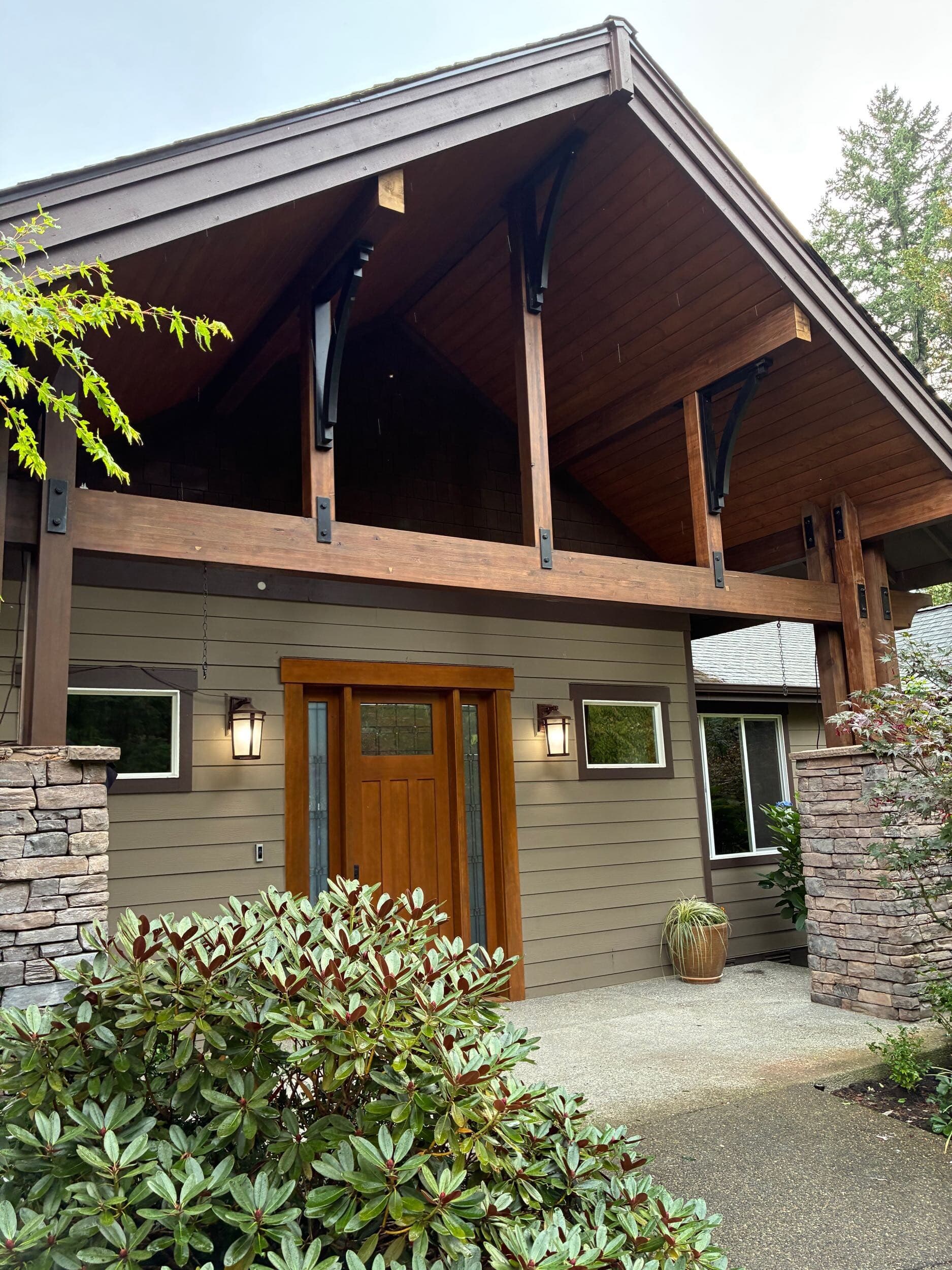 Home entry with stained timber beams, stone columns, and wood front door