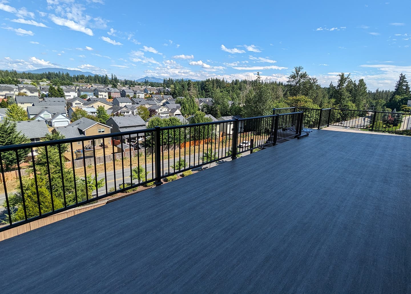 Wide deck with black metal railing overlooking a residential valley